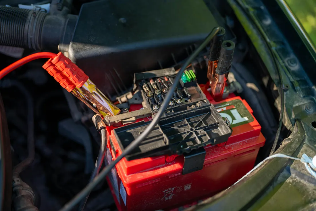 Alternator replacement — battery with jumper cables in the engine bay